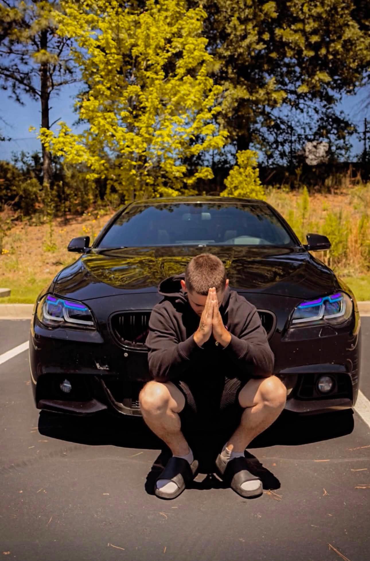 Polo crouched in front of a blacked-out BMW with color-shift headlights